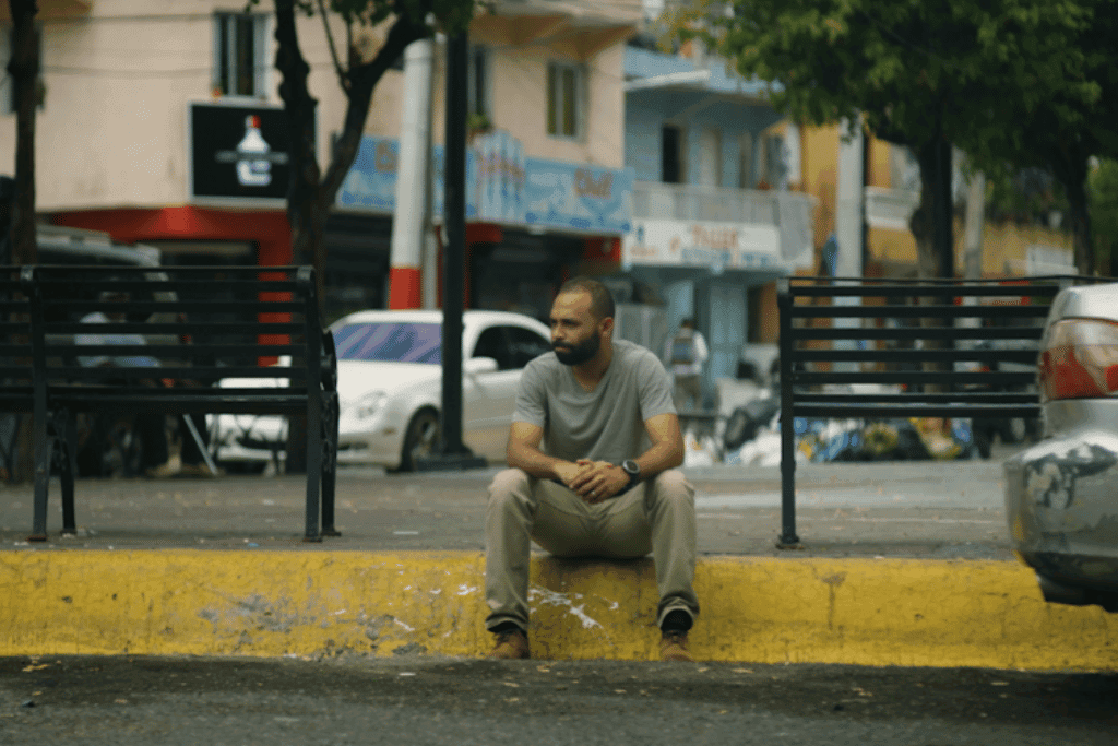Jonathan sits on the kerb. He looks contemplative.