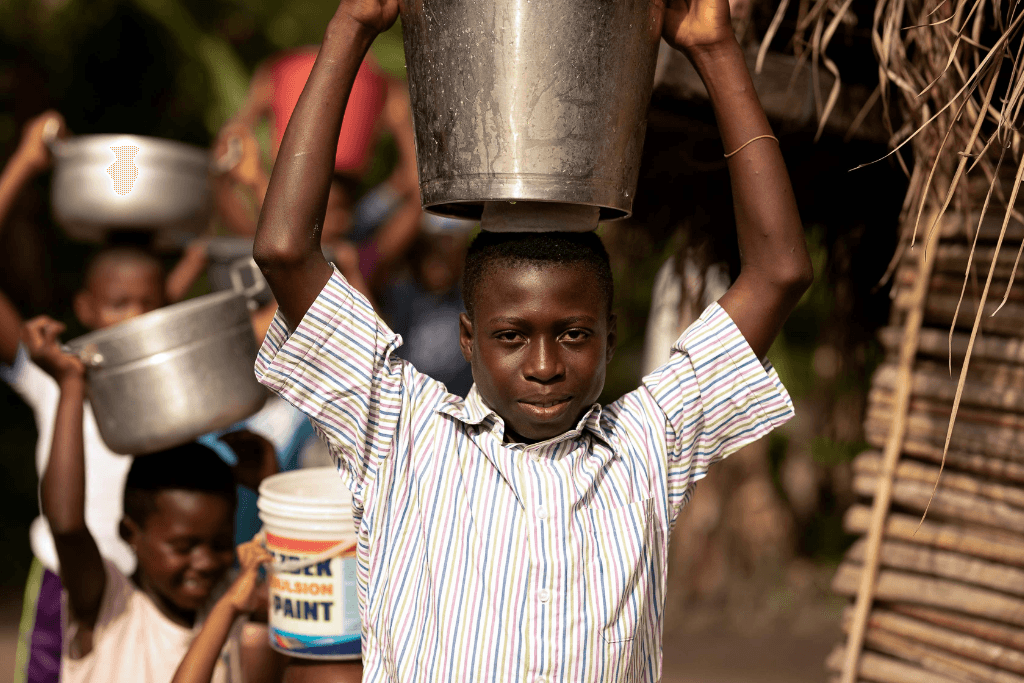 Larry, 11, Ghana is pictured carrying some water