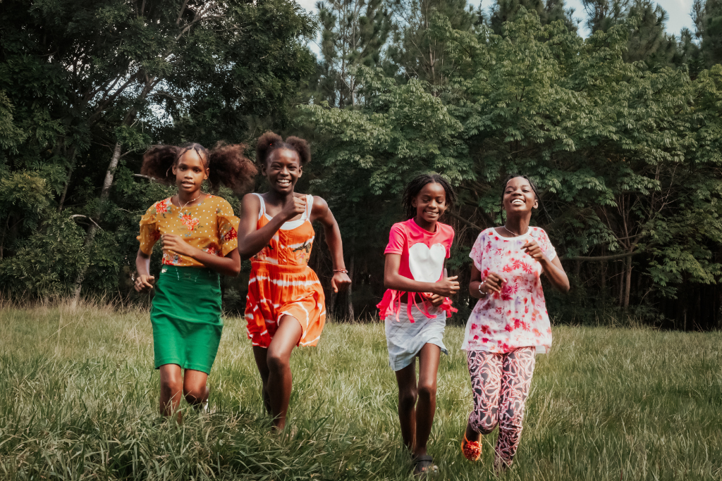 Lisbeth, Lauri, Laurelis, and Fracieli smiling and running on grass