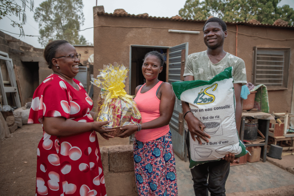 Benoit (right), his step mother, and a staff member receiving emergency food from the Compassion project