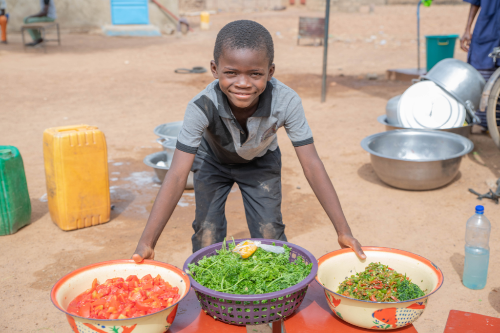 Fabrice poses with the fresh vegetables that the cook at the poject will use to prepare lunch, Burkina Faso