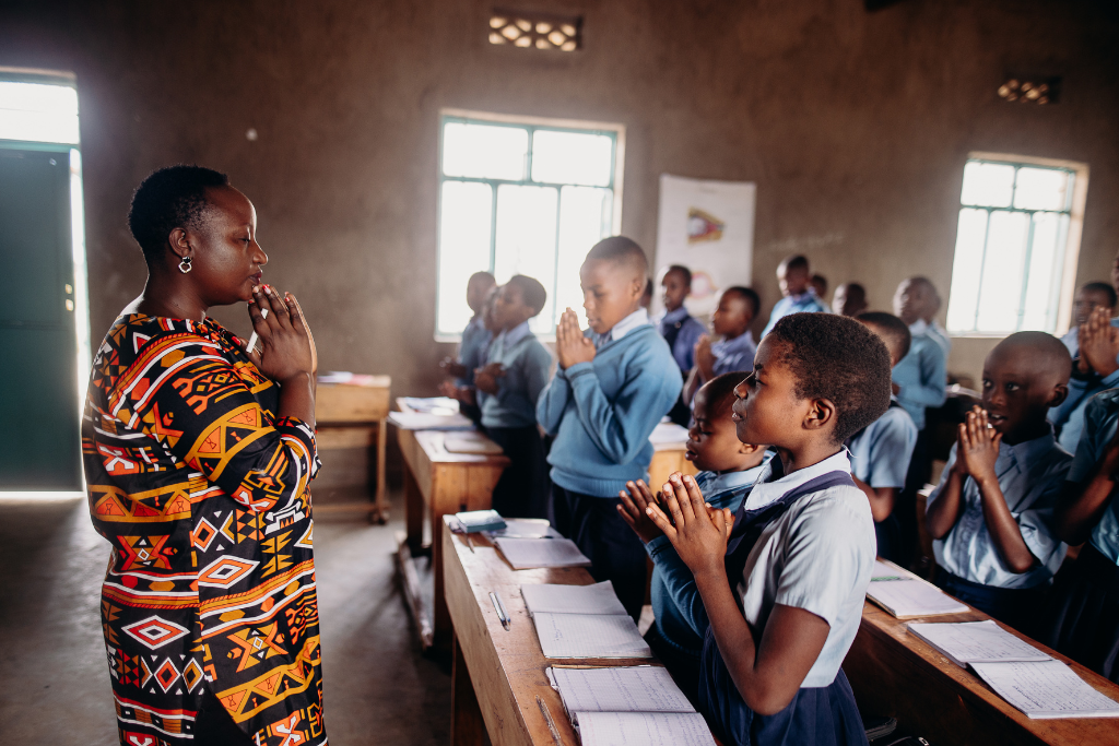 Justine leads a classroom full of students in prayer